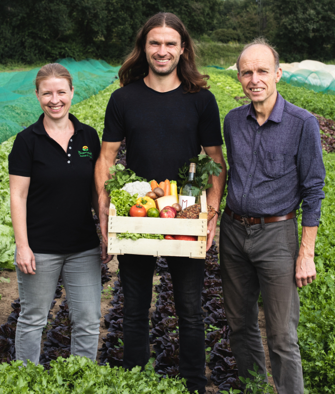 Eva, Julian und Josef halten eine Bio-Kiste mit Produkten aus dem Biomobil-Onlineshop